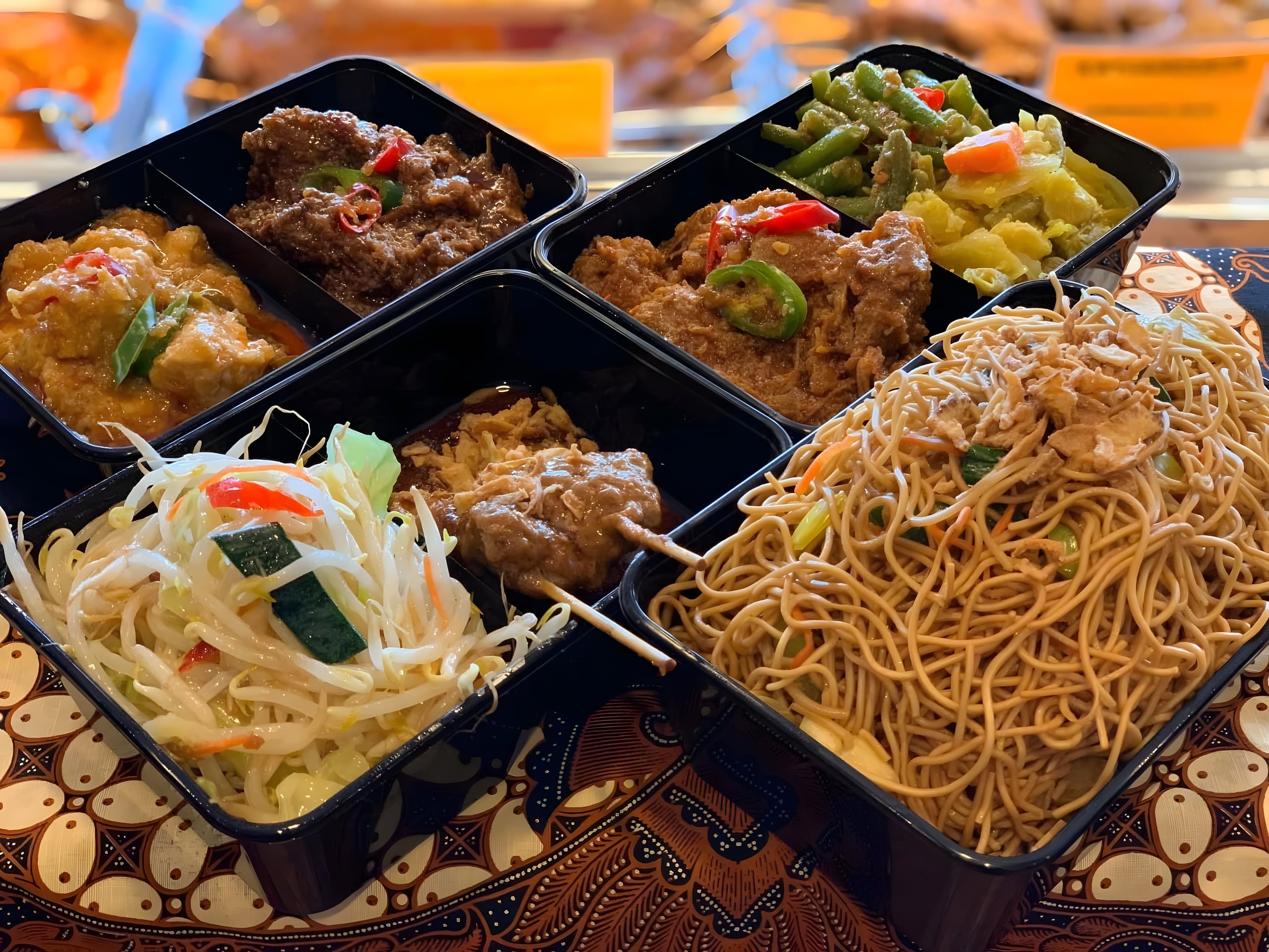 Afhaalbakjes met verse Indonesische gerechten van Toko Tropical, waaronder saté, bami goreng en groenten